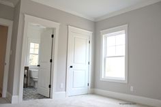 an empty room with two white doors and a toilet in the corner on the far side