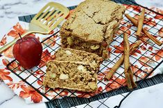 two pieces of cake on a cooling rack with an apple and cinnamon stick next to it