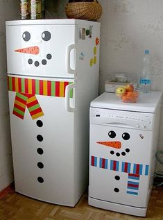 two refrigerators are decorated like snowmen and one has a bow on its head