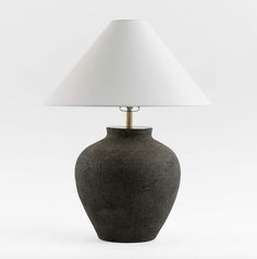 a black table lamp with a white shade on the base and a light bulb in front of it