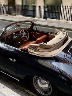 an old black convertible car parked on the side of the road next to a building