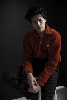 a man sitting on top of a toilet in a dark room with his hand on the seat