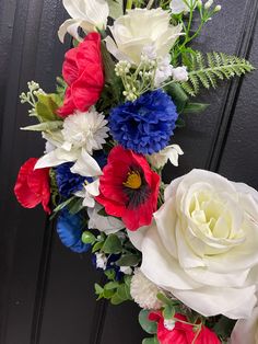 a bouquet of red, white and blue flowers is hanging on the front door handle