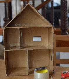 an open cardboard house sitting on top of a wooden table