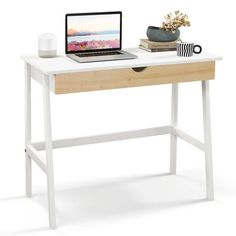 a laptop computer sitting on top of a white desk next to a cup and plant