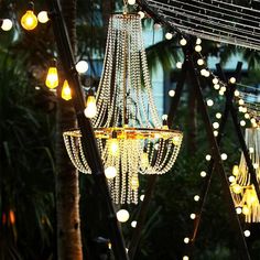 several chandeliers hanging from the ceiling in front of trees with lights on them