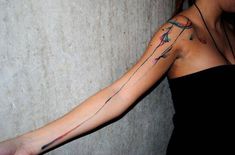 a woman with a cross tattoo on her left arm and right arm is leaning against a wall