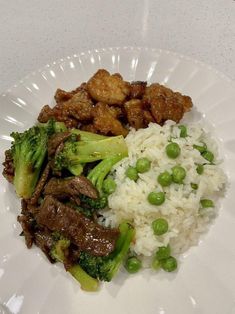 a white plate topped with rice, meat and broccoli