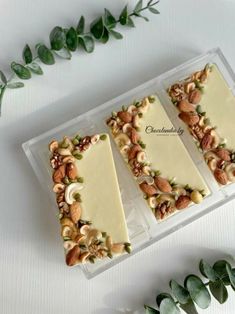 three slices of cheesecake with nuts and green leaves on the table next to it