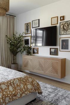 a bed room with a neatly made bed and a flat screen tv mounted to the wall