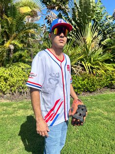 a man standing in the grass holding a catchers mitt and wearing sunglasses on his head