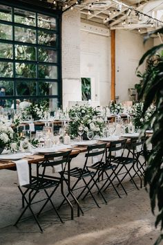 a long table with white flowers and greenery is set up for a wedding reception