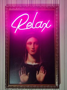 a pink neon sign that says relax on the side of a wall with a woman's hand in front of it