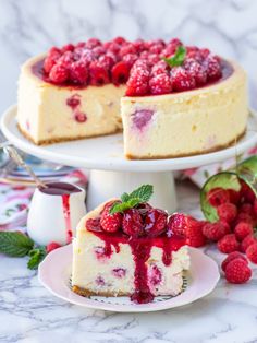 a cheesecake with raspberry sauce and fresh berries on the side, ready to be eaten