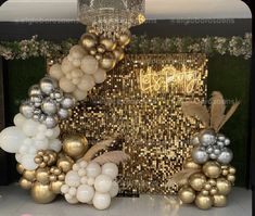 balloons and decorations are arranged on the floor in front of a gold - colored backdrop