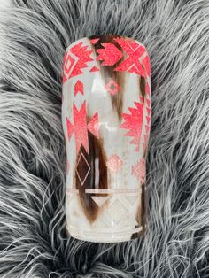 a glass vase with red and white designs on it sitting on a furry surface in front of a black background