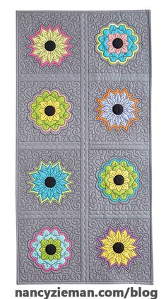 four squares with flowers on them in different colors and sizes, all made up of grey fabric