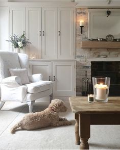 a dog laying on the floor in front of a living room with white furniture and fireplace