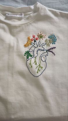 an embroidered t - shirt with flowers in the shape of a human head on it