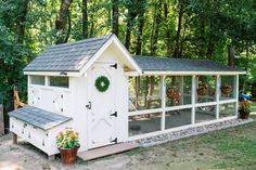 a white chicken coop with a wreath on the door and windows in front of it