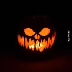 a carved pumpkin with an evil face on it's side, lit up in the dark