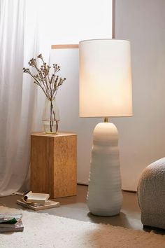 a table lamp sitting on top of a wooden block next to a vase filled with flowers