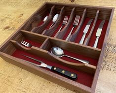 a wooden tray with utensils and spoons in it