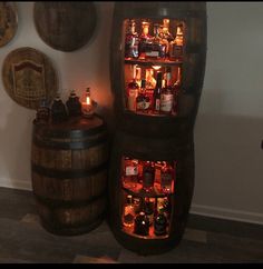 two wooden barrels filled with liquor bottles next to a wall mounted wine bottle display case