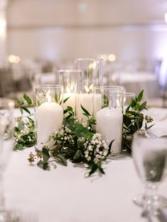 candles and greenery are arranged on the table