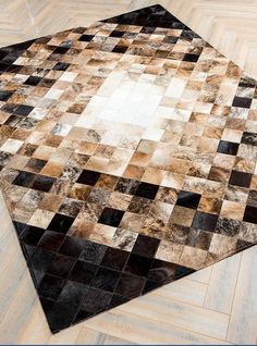 an area rug made out of patchwork squares on wood flooring with white and black accents