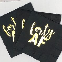 two black napkins with gold foil lettering on them