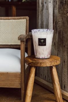 a white candle sitting on top of a wooden stool