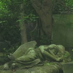 a statue is laying on the ground next to a tree