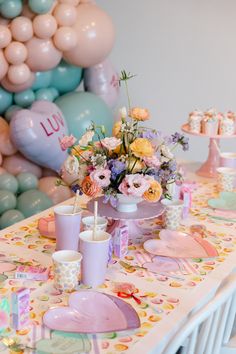 a table set up with balloons, plates and cups