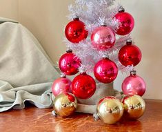 a small christmas tree with red and gold baubes on it's base