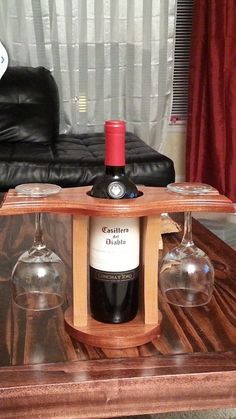 there is a wine bottle and two glasses on the table in front of a couch