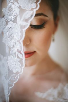 a woman wearing a veil and looking down at her wedding dress with the lace on it