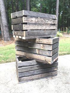 three wooden crates stacked on top of each other in front of trees and grass area