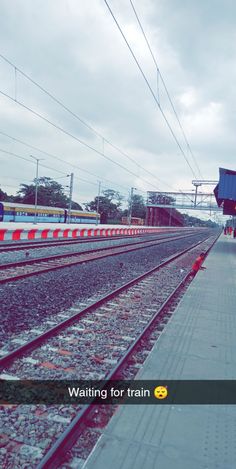 an empty train station with no people on the platform and one person waiting for the train