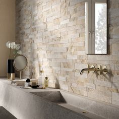 a bathroom with a stone wall and sink in front of the window, next to a mirror