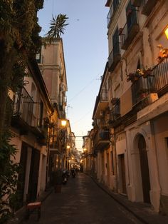 an alley way with several buildings and lights on either side, one building has balconies