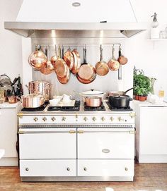 a kitchen with pots and pans hanging on the wall next to an open oven