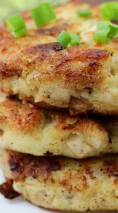 three crab cakes stacked on top of each other with scallions and green onions