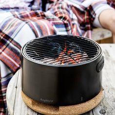 a person laying on a bed next to an outdoor bbq with the lid open