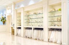 there are many white shelves with wedding dresses on them