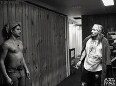 black and white photograph of two men walking down the hallway in front of a wooden wall