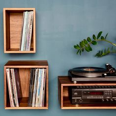 a record player and two wooden shelves with vinyl records on them against a blue wall