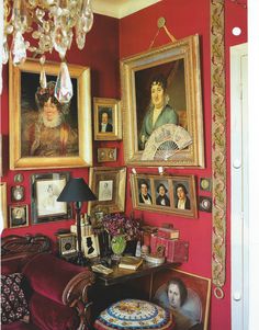 a living room with red walls and paintings on the wall