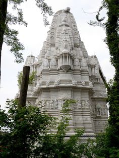 a tall white building with statues on it's sides and trees in the foreground