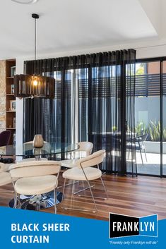 the black sheer curtain is hanging in front of the glass table and chairs, which are surrounded by wood flooring